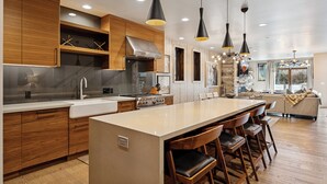 A modern kitchen with wooden cabinets, a large island, and pendant lighting.