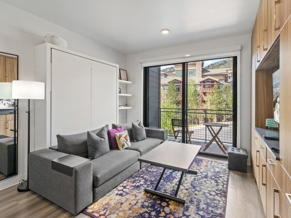 Un salon moderne avec un canapé gris, une table basse et un tapis à motifs.