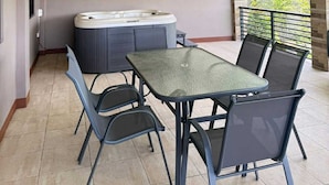 Ein überdachter Patio-Bereich mit Whirlpool, Tisch und Stühlen.