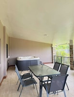 Un patio cubierto con un jacuzzi, una mesa y sillas.