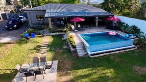 Ein Wohnhaus mit Pool, Sitzgelegenheit im Freien und einer überdachten Terrasse.