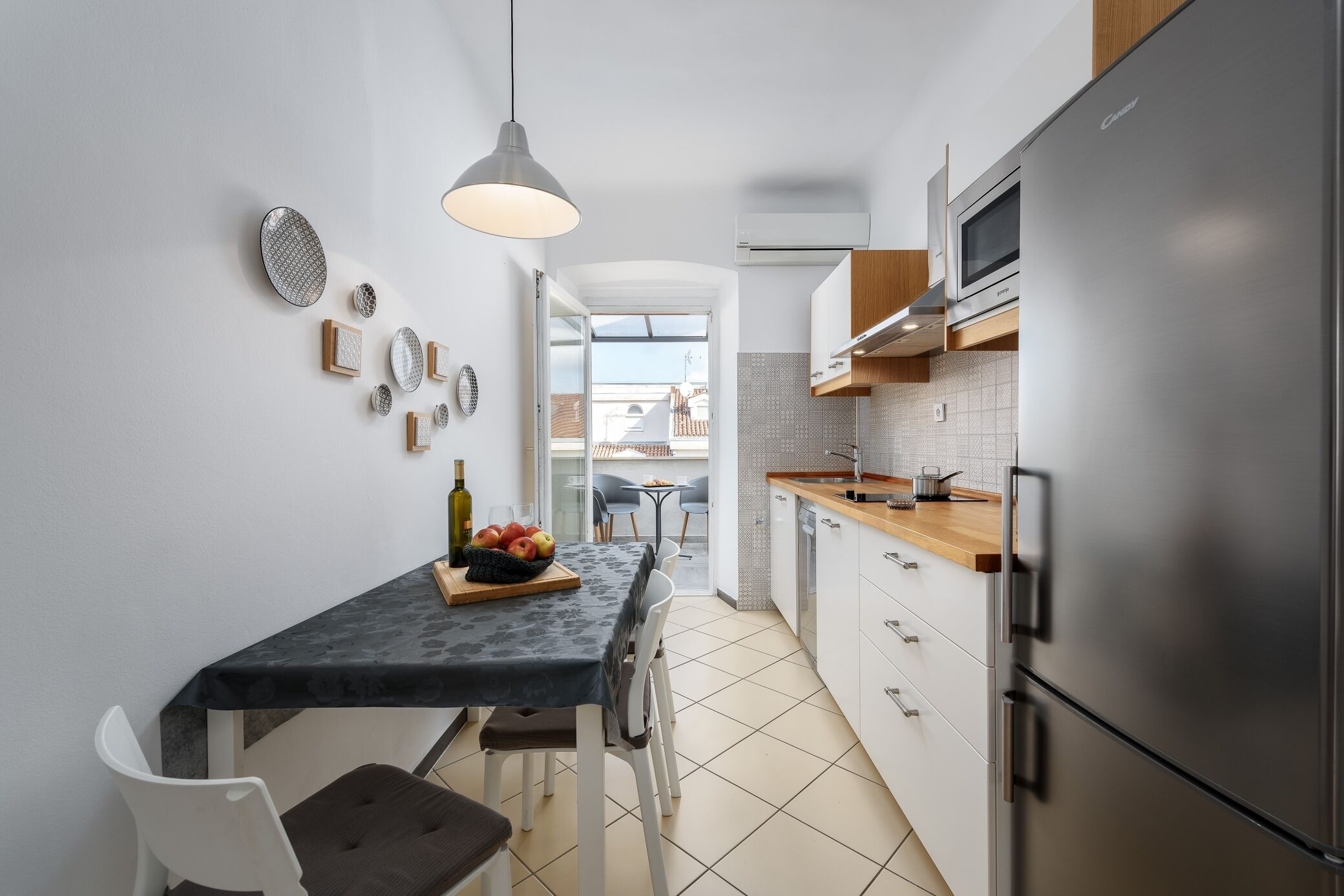 A modern kitchen with a dining area, stainless steel appliances, and a view to the outside.
