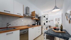 Eine moderne Küche mit weißen Schränken, einer Holz Arbeitsplatte und einem eingebauten Geschirrspüler.