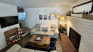 A living room with a sofa, coffee table, fireplace, and a bookshelf. - Sunny Retreat | Near Beaches & Trails | Sleeps 6 (South Lake Tahoe)