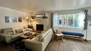 A living room with a fireplace, a sofa set, a wooden coffee table, and a bench. - Sunny Retreat | Near Beaches & Trails | Sleeps 6 (South Lake Tahoe)