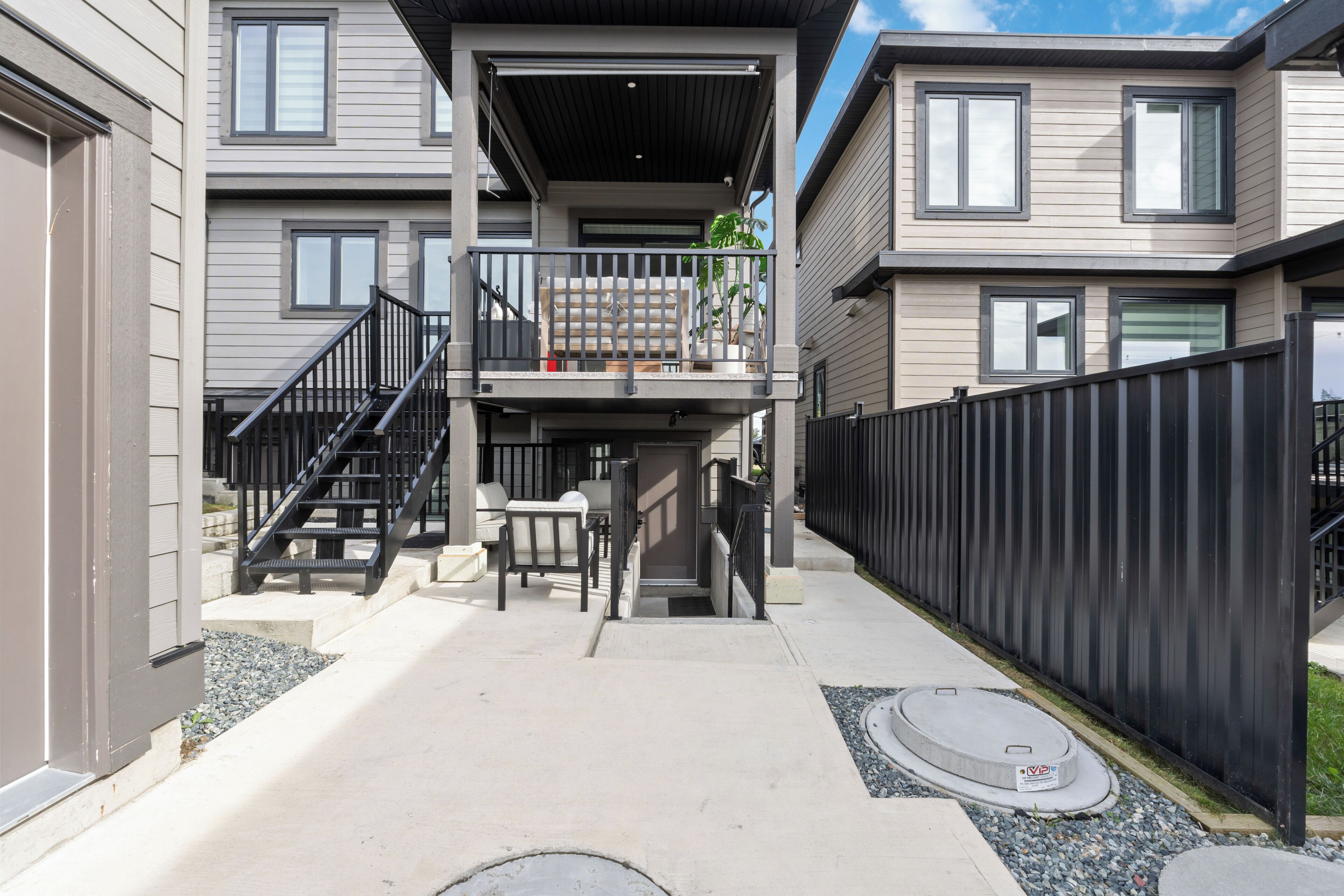 Un edificio residencial con un espacio exterior cubierto, una escalera y un patio cercado.