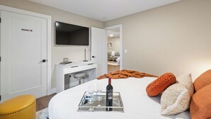 Habitación de hotel con cama, escritorio, televisor y puerta privada.