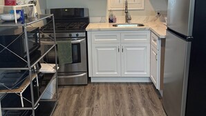 Une cuisine moderne avec des armoires blanches, des appareils en acier inoxydable et un plancher en bois.