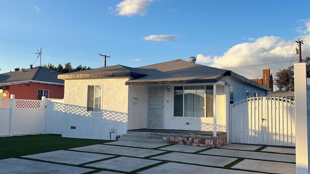 Il s’agit d’une propriété résidentielle dotée d’une allée pavée, d’une clôture blanche et d’une petite maison avec un garage.