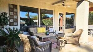 A covered patio area with wicker furniture, a sofa, and a table. - Coachella Walkable | Tuscan Villa | Pool Sleeps 12 (Indio)