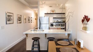 Una cocina moderna con una isla central, electrodomésticos de acero inoxidable y una zona de comedor con taburetes.