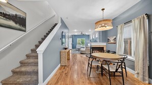 A modern interior with a staircase, a dining area with a round table and chairs, and a fireplace.