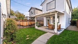 A residential backyard with a covered patio, a wooden fence, and a lawn.