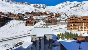 En snötäckt bergsanläggning med trähus och en skidlift.