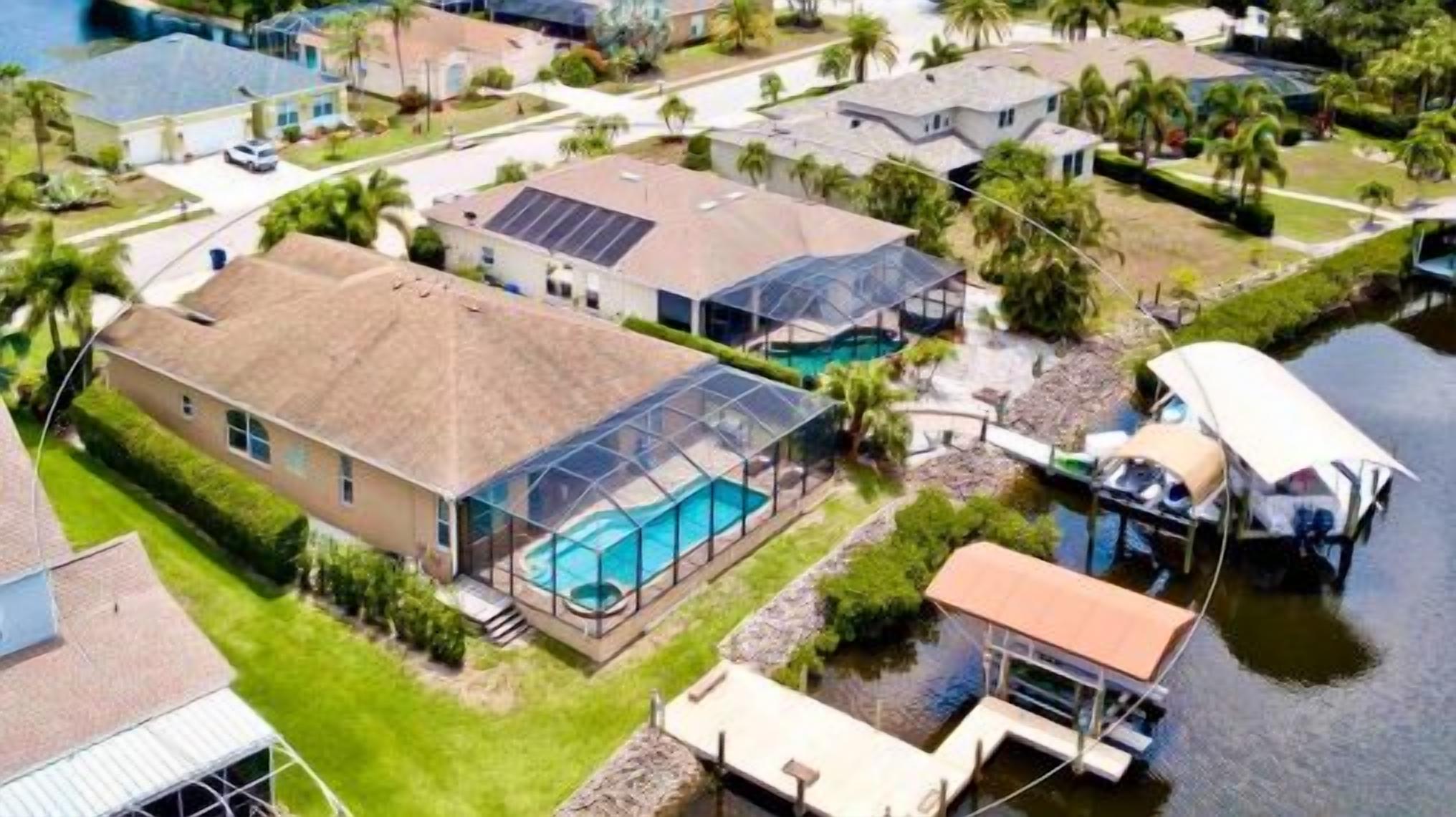 An aerial view of a residential area with houses, a swimming pool, and a boat dock.