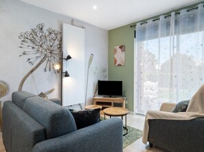 Ein modernes Wohnzimmer mit einer Couch, einem Sessel und einem Flachbildfernseher auf einem Holzboden.
