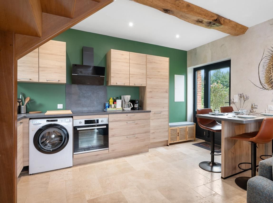 Una cocina moderna con armarios de madera, lavadora integrada y comedor con mesa y sillas.
