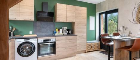 Una cocina moderna con armarios de madera, lavadora integrada y comedor con mesa y sillas.