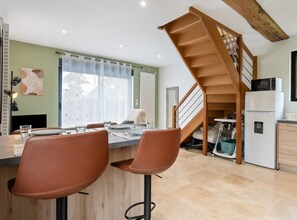 Eine moderne Küche mit einer Holztreppe, einem Essbereich mit zwei Stühlen und einer Kücheninsel.