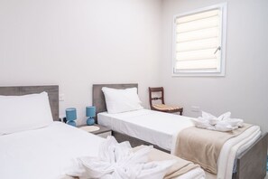 A hotel room with two beds, a window with blinds, a chair, and towels on the floor. - Ghajnsielem Retreat 4 Bedrooms Panoramic Terrace (Ghajnsielem)