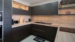 A modern kitchen with dark cabinetry, a wooden countertop, and a built-in sink. - Ghajnsielem Retreat 4 Bedrooms Panoramic Terrace (Ghajnsielem)