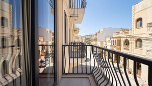 A balcony with a view of a residential area, featuring a metal railing and a clear sky. - Ghajnsielem Retreat 4 Bedrooms Panoramic Terrace (Ghajnsielem)