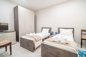 A hotel room with two beds, a TV, a wardrobe, and a desk. - Ghajnsielem Retreat 4 Bedrooms Panoramic Terrace (Ghajnsielem)