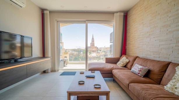 A modern living room with a large flat-screen TV, a wooden coffee table, and a brown leather sofa. - Ghajnsielem Retreat 4 Bedrooms Panoramic Terrace (Ghajnsielem)