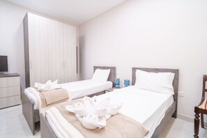 A hotel room with two single beds, a wardrobe, a TV, and a chair. - Ghajnsielem Retreat 4 Bedrooms Panoramic Terrace (Ghajnsielem)