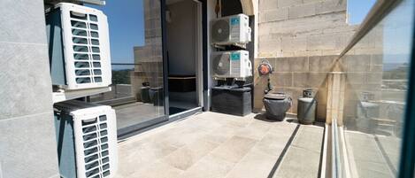 A balcony with air conditioning units, a trash bin, and a water dispenser.