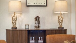 Een ontvangstgedeelte met twee wandlampen, een bord met de tekst 'MONTANA', een decoratieve vaas en een presentatie van 'Fever-Tree' flessen.