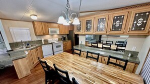 Eine Küche mit Holzausbau, einer Granitarbeitsplatte, einem eingebauten Herd und einem Essbereich mit einem Holztisch und Stühlen.