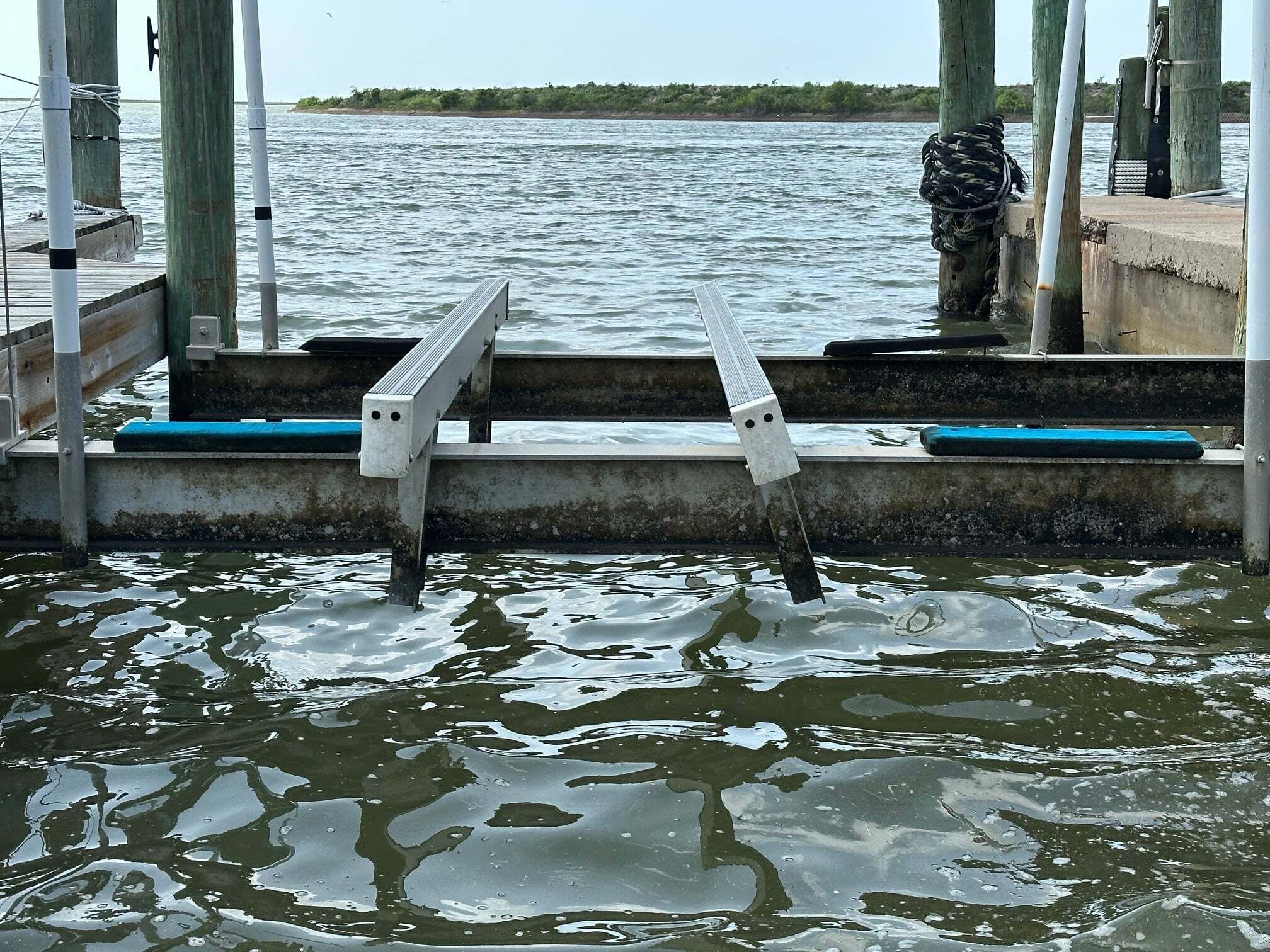 Une jetée dotée d’une rambarde métallique, d’escaliers en béton et d’une plateforme en bois qui s’avance sur une étendue d’eau.