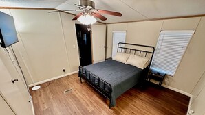 Ein Schlafzimmer mit einem Bett, einem Deckenventilator und einem Fenster mit Jalousien.