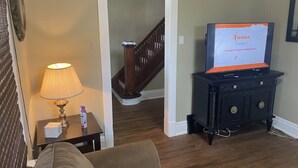 A living room with a TV displaying the NBA Playoffs, a lamp, a small table with a tissue box, and a staircase. - Exceptionally Close to the Falls (Niagara Falls)