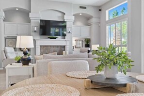 A modern living room with a fireplace, comfortable seating, and a large window with a view.