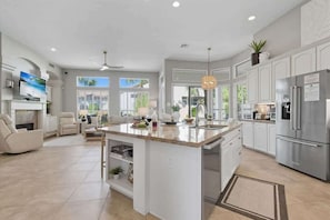 A modern kitchen with a central island, white cabinetry, and stainless steel appliances.