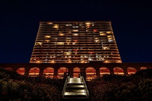 Un edificio de gran altura con múltiples balcones, una escalera central y ventanas de arco.