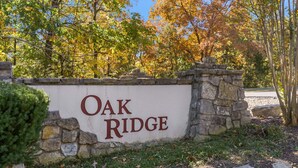 Un letrero con la inscripción 'OAK RIDGE', rodeado de muros de piedra y árboles.