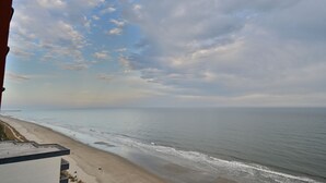 Blick auf einen Strand, einen klaren Himmel und einen entfernten Steg.