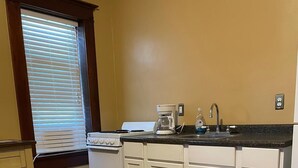 A compact kitchen with white cabinets, a stove, a coffee maker, and a sink. - Cozy Private Room in Historic Findlay Home with Kitchen, Wifi and Free Parking (Findlay)