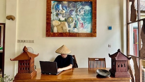 Une personne utilise un ordinateur portable sur une table en bois, à côté de lanternes en bois traditionnelles et d’une décoration murale.