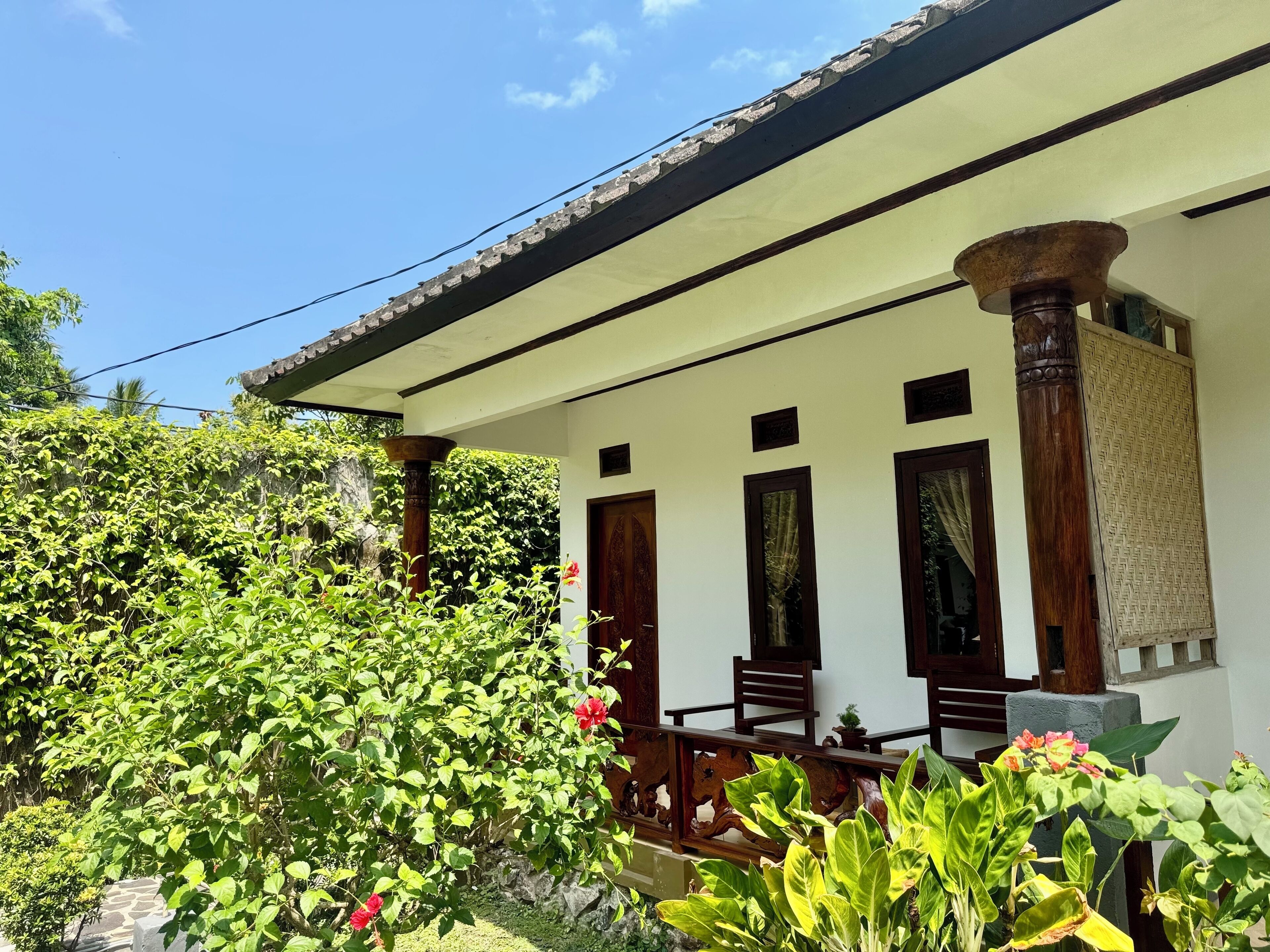 A traditional building with a porch, wooden columns, and a stone wall.