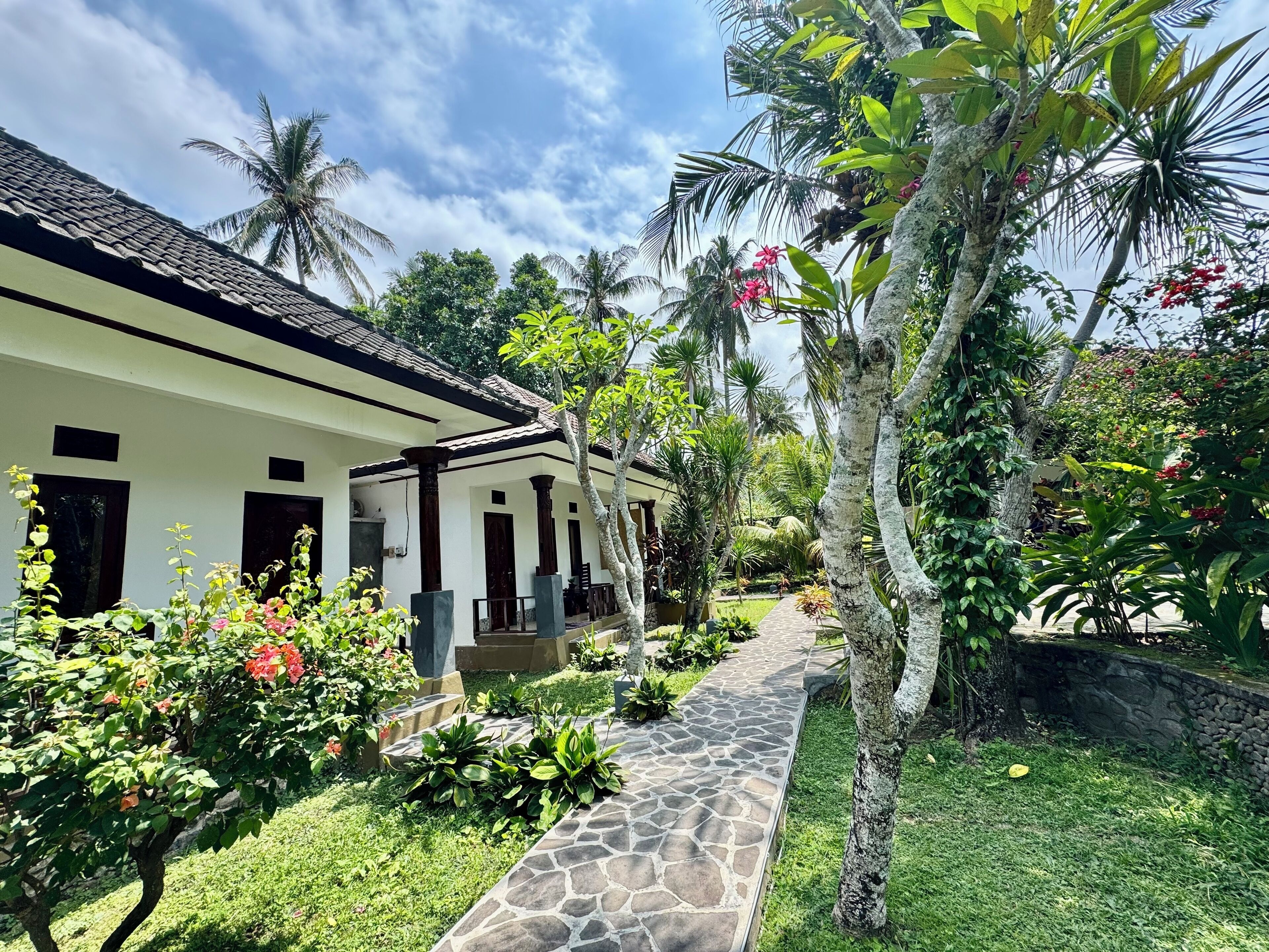 A tropical-style house with a tiled roof and a stone pathway leading to the entrance.