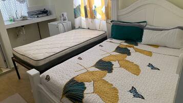 Un dormitorio con cama, una mesita de noche pequeña y una ventana con cortinas.