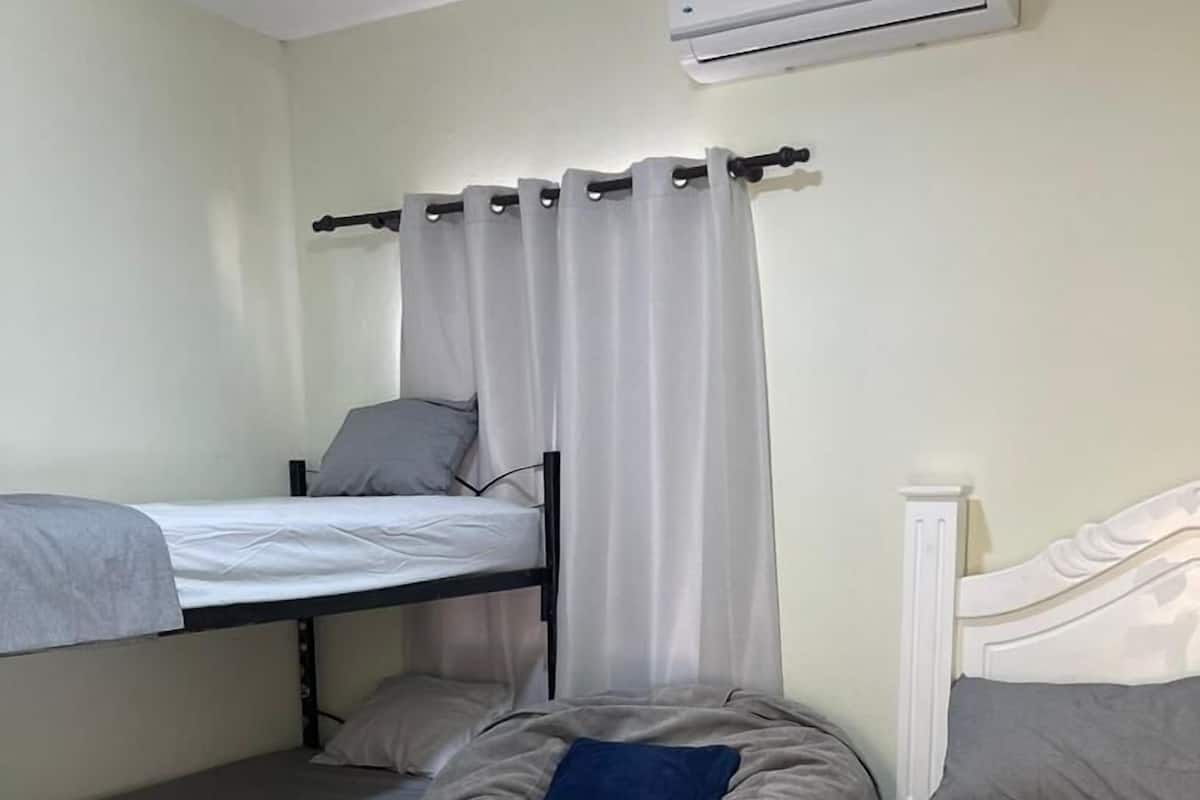 A dormitory room with bunk beds, a bean bag chair, and an air conditioning unit.