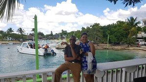 Una pareja en una cubierta de madera con vistas a un puerto deportivo con barcos y palmeras.