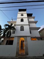 A multi-story building with a central entrance, balconies, and a gated front door.