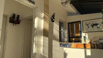 A hotel entrance with a sign reading 'El Navegante Hotel,' a fan on the ceiling, and a window with a view.