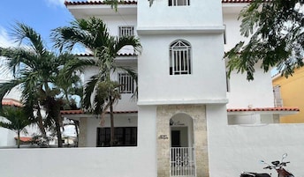 A white building with a central archway entrance, multiple windows, and a balcony.